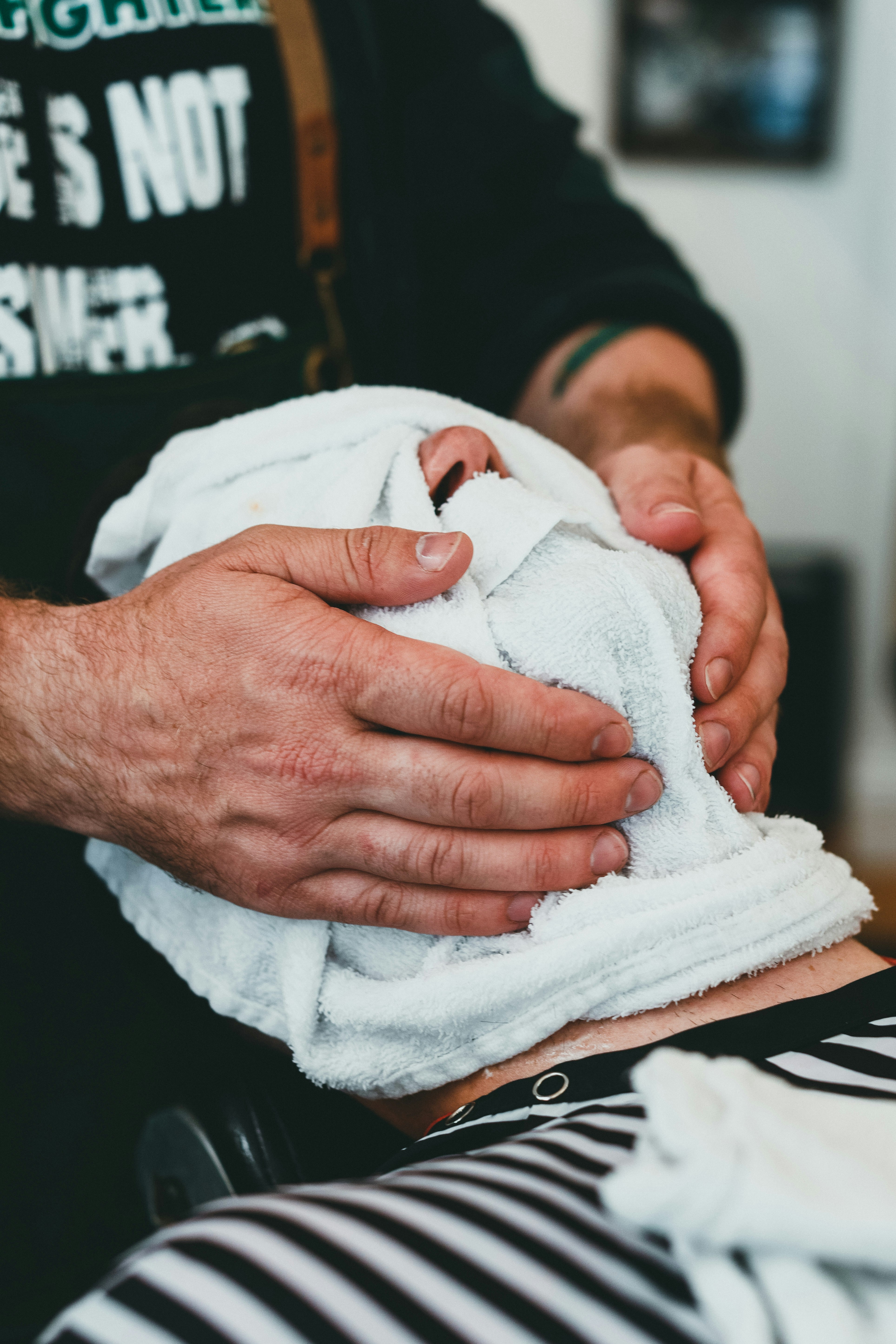 A person receiving a hot towel shave in a barbershop.